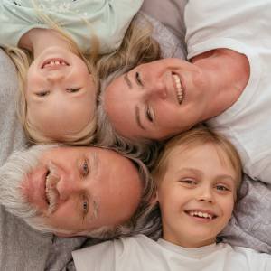 Avós deitados ao lado dos dois netos, todos sorrindo