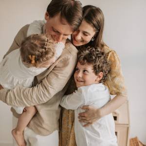 Pai e mãe abraçando os dois filhos pequenos